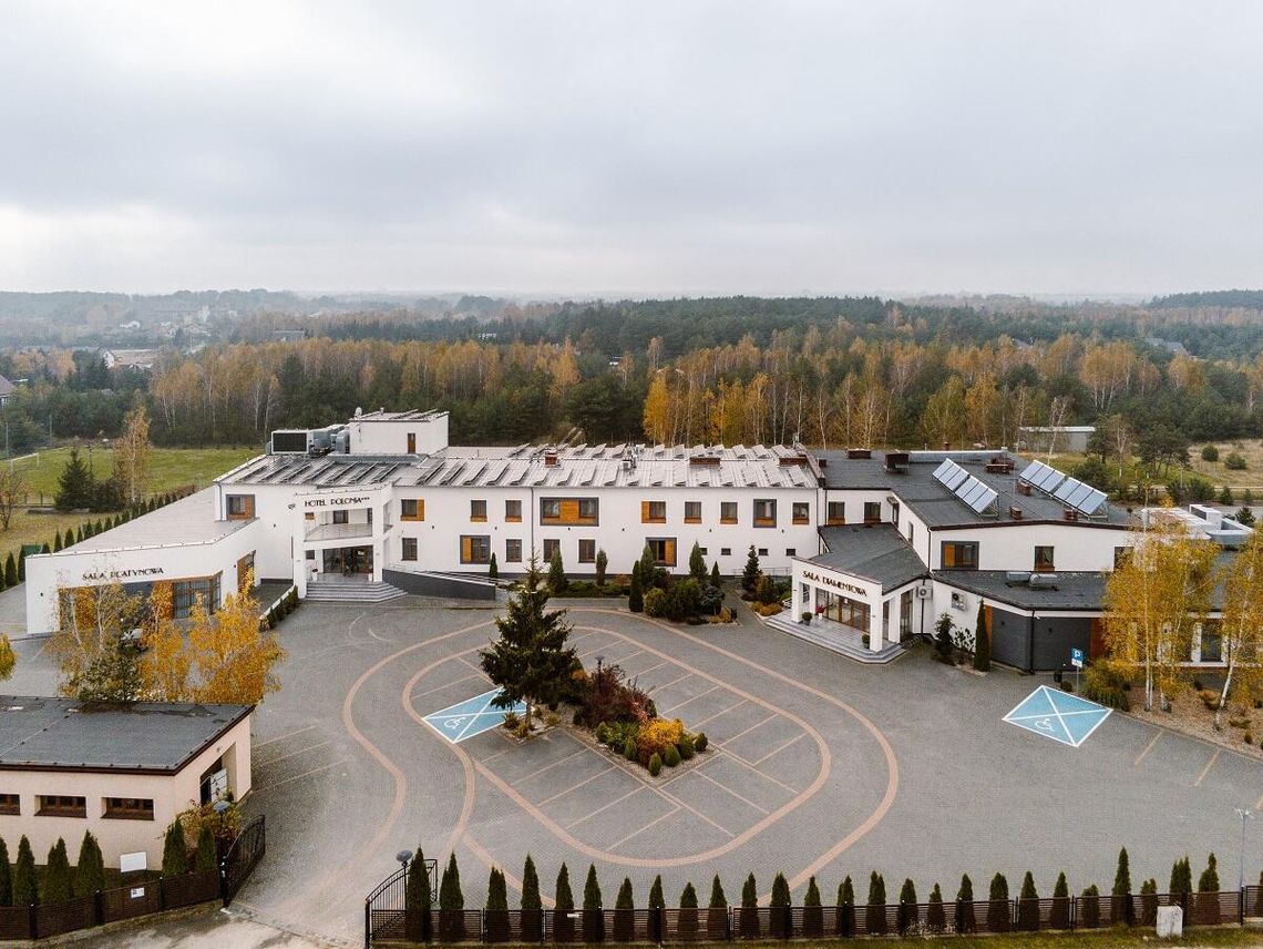 Walerian Pawluczuk Krzysztof Dobrowolski Polonia Spółka jawna – Hotel Polonia Zdjęcie z lotu ptaka przedstawiające nowoczesny budynek Hotelu Polonia*** w Grabanowie, z widocznym głównym wjazdem, parkingiem oraz otaczającym go zalesionym terenem.